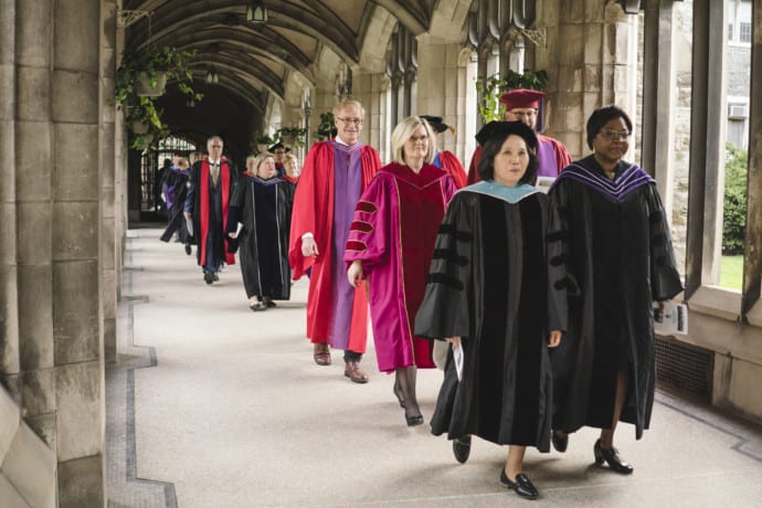 faculty in robes walking down hallway
